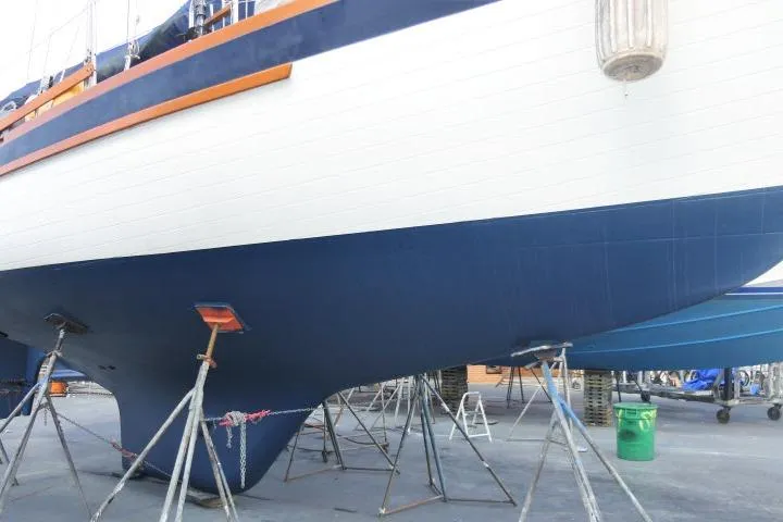 Slide: The Image of 1982 Formosa 42 sailboat on stands, blue and white hull, docked for maintenance. - 21