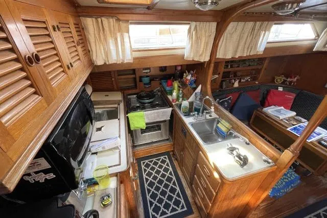 Slide: The Image of 1982 Formosa 42 yacht interior with wooden cabinetry, kitchen, and seating area. - 7