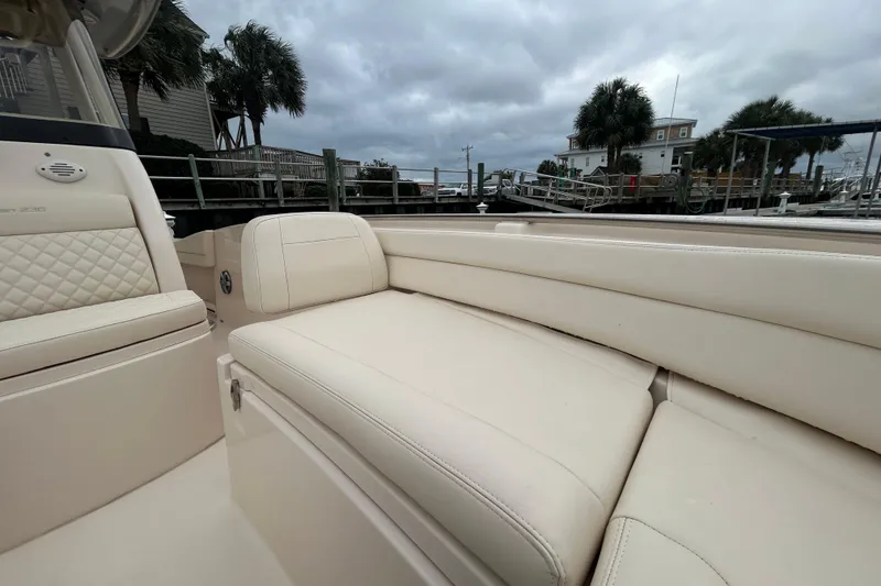 Slide: The Image of 2025 Grady-White Fisherman 236 boat interior with beige seating, docked near palm trees. - 20