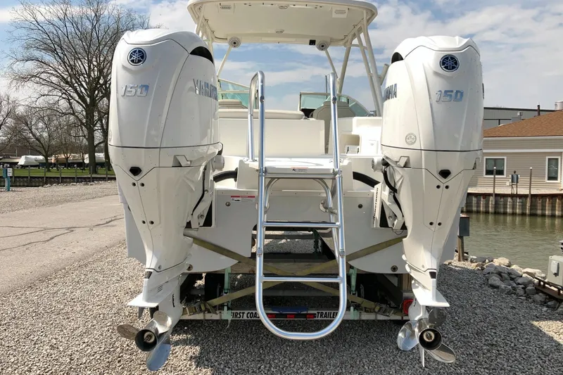 Slide: The Image of 2026 World Cat 230 SD boat with dual Yamaha 150 engines, docked on gravel. - 3
