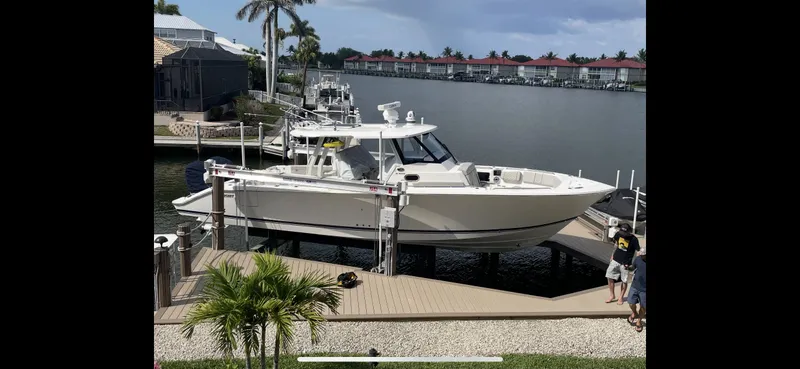 The Image of 2023 Pursuit S 358 Sport boat docked by waterfront homes. - 0