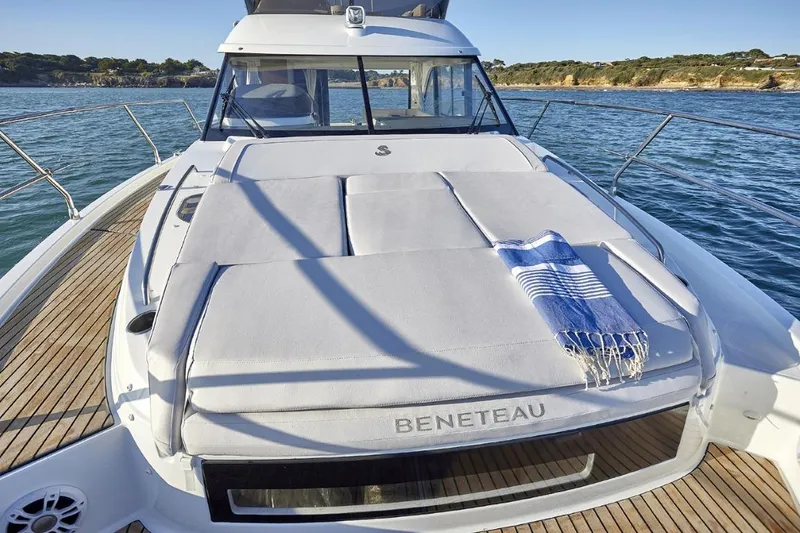 Slide: The Image of 2026 Beneteau Antares 12 Fly OB yacht with sunbed and towel on deck. - 2