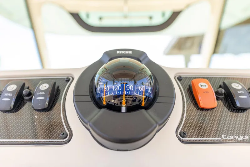 Slide: The Image of Compass and controls on 2022 Grady-White Canyon 336 boat dashboard. - 22