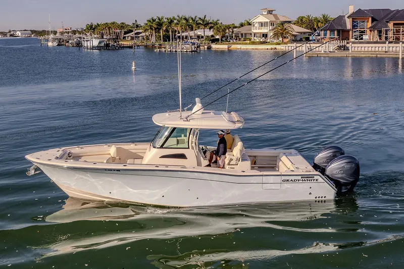 Slide: The Image of 2022 Grady-White Canyon 336 boat cruising on a serene waterfront with luxury homes. - 5