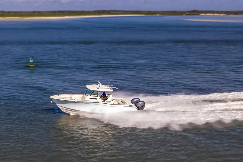 Slide: The Image of 2022 Grady-White Canyon 336 boat cruising on open water, creating a wake. - 52