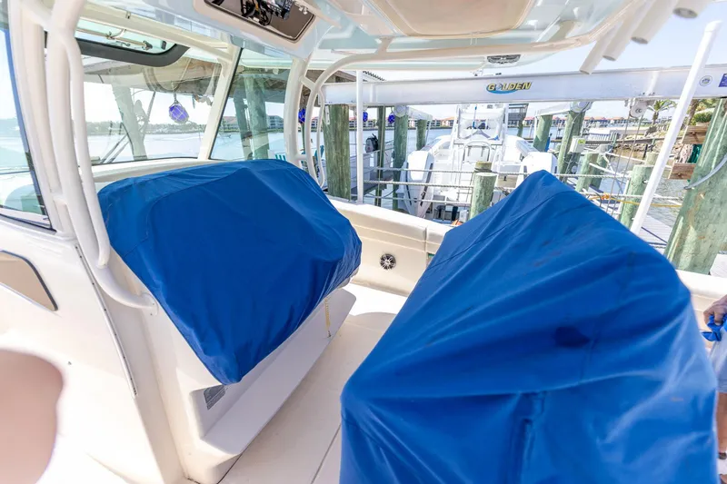 Slide: The Image of 2022 Grady-White Canyon 336 boat interior with blue-covered seats at a marina. - 53
