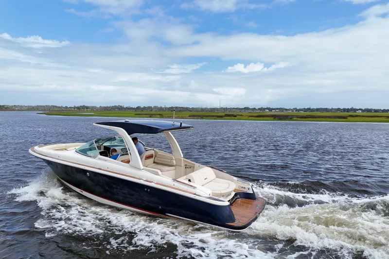 Slide: The Image of 2020 Chris-Craft Launch 31 GT cruising on a scenic waterway under a blue sky. - 107
