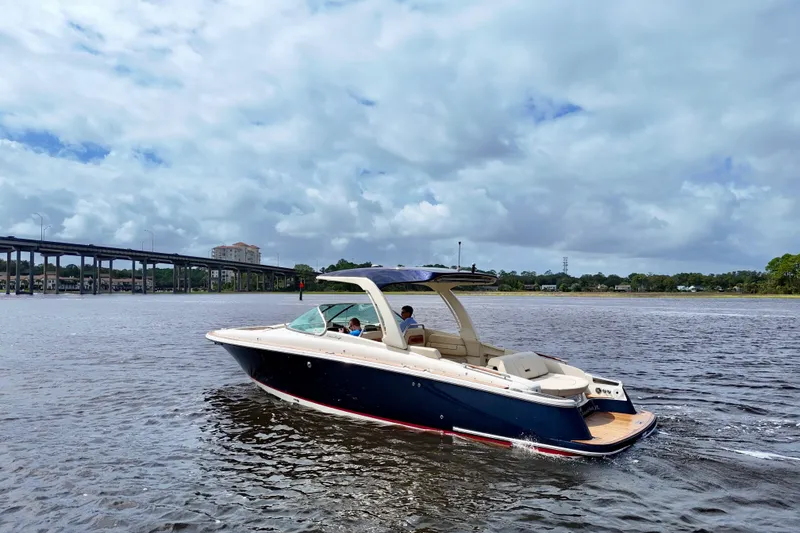 Slide: The Image of 2020 Chris-Craft Launch 31 GT boat cruising on a scenic river under a cloudy sky. - 22
