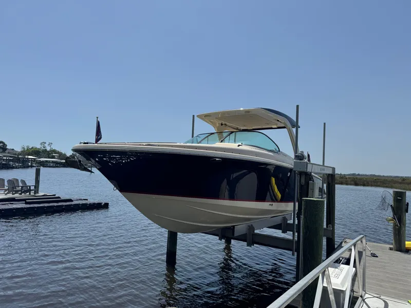 Slide: The Image of 2020 Chris-Craft Launch 31 GT boat docked on a lift by the water. - 32