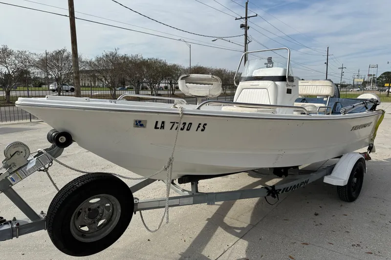 Slide: The Image of 2007 Triumph 170CC boat on trailer, parked outdoors, showcasing sleek design and white exterior. - 4