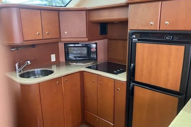 Slide: The Image of 2006 Silverton 39 Motor Yacht kitchen with wood cabinets, sink, microwave, and refrigerator. - 9