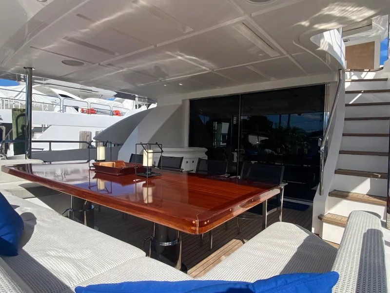 Slide: The Image of Outdoor dining area on a 2014 Azimut 100 Grande yacht with wooden table and cushioned seating. - 11