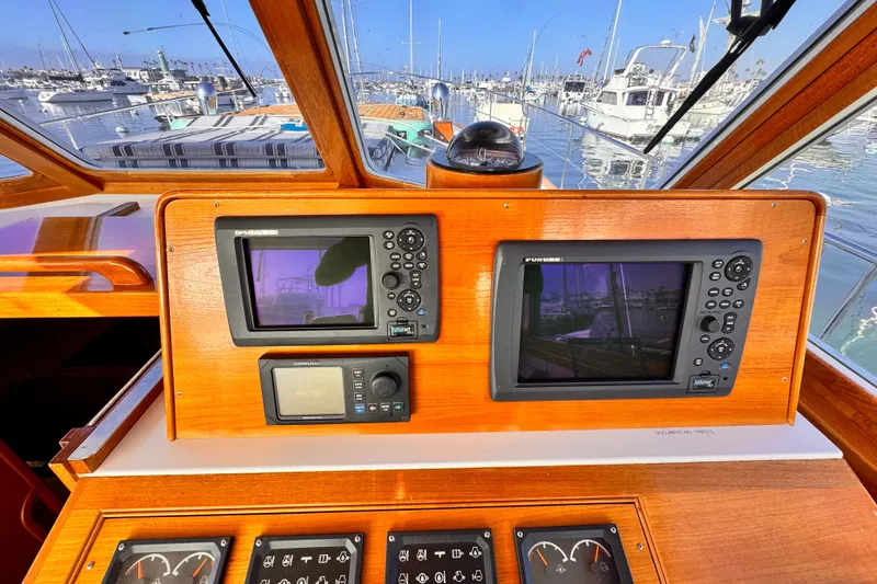 Slide: The Image of Cockpit of 2000 Grand Banks East Bay 49 with navigation equipment and marina view. - 5