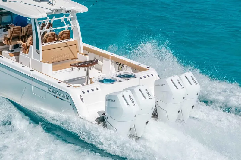 Slide: The Image of Manufacturer Provided Image: 2025 Caymas 44 CT boat with powerful Mercury engines cruising on clear blue water. - 2