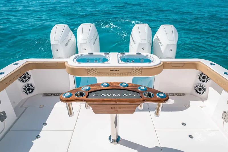 Slide: The Image of Manufacturer Provided Image: 2025 Caymas 44 CT boat deck with four engines, rod holders, and ocean view. - 7
