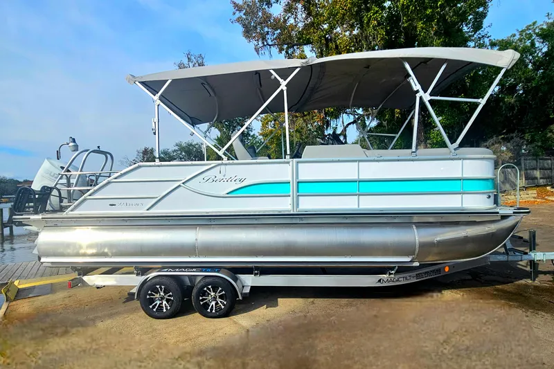Slide: The Image of 2026 Bentley Pontoons Legacy 223 Swingback on trailer, featuring sleek design and canopy. - 2