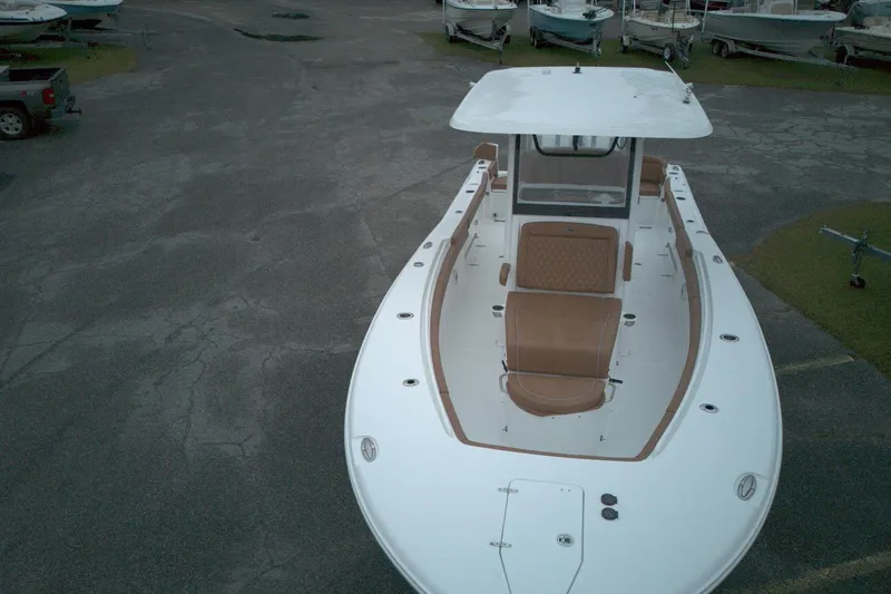 Slide: The Image of 2026 Sea Hunt Ultra 285 Coffin Box boat with tan seating, docked on pavement. - 2