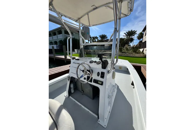 Slide: The Image of 2012 Majek Illusion 226 boat console with steering wheel and controls, docked near waterfront homes. - 17