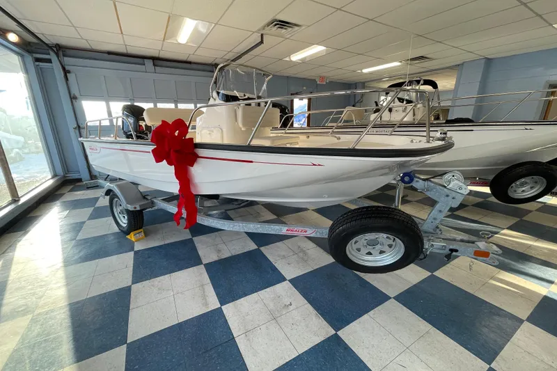 Slide: The Image of 2026 Boston Whaler 150 Montauk with red bow in showroom. - 3