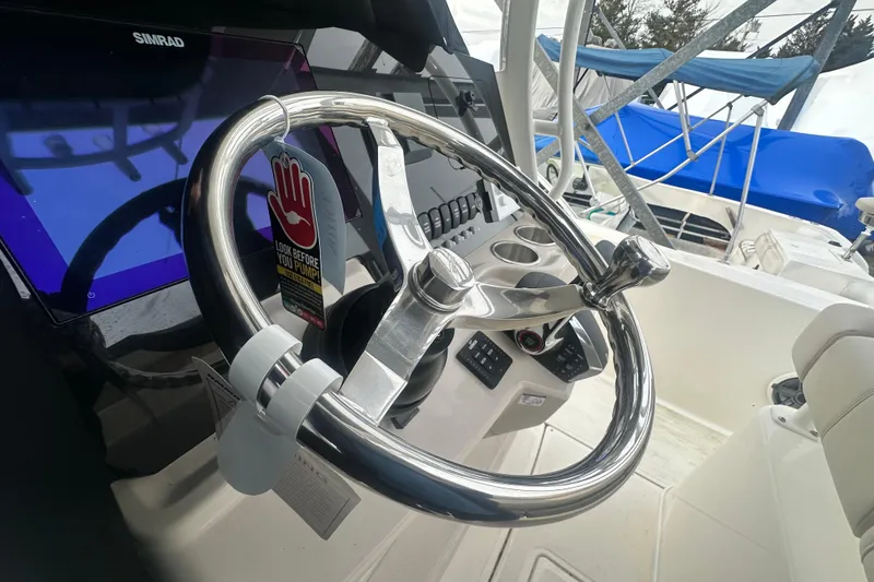 Slide: The Image of Boston Whaler 220 Dauntless 2025 helm with shiny steering wheel. - 14