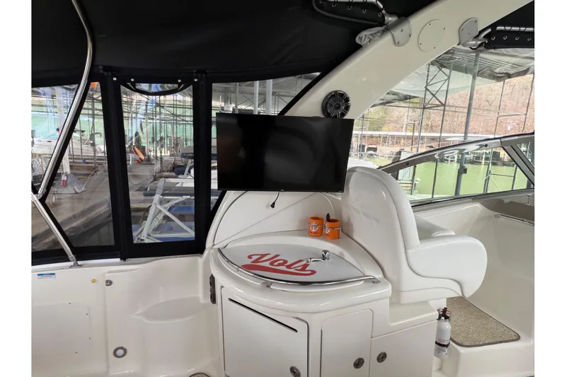 Slide: The Image of 2007 Sea Ray 340 Sundancer interior with TV, sink, and seating in a marina setting. - 8