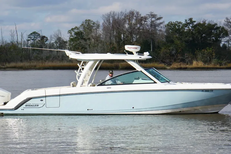 The Image of 2021 Boston Whaler 320 Vantage boat on calm water, surrounded by trees. - 1