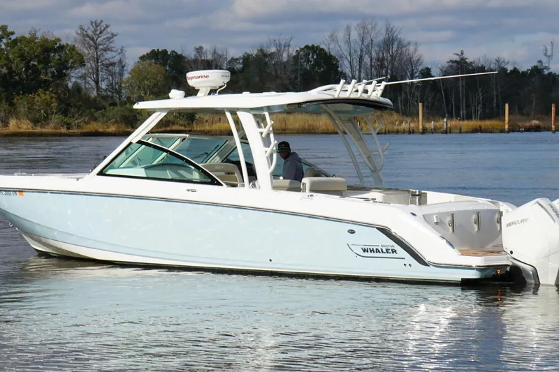 Slide: The Image of 2021 Boston Whaler 320 Vantage boat on calm water, featuring sleek design and twin engines. - 10
