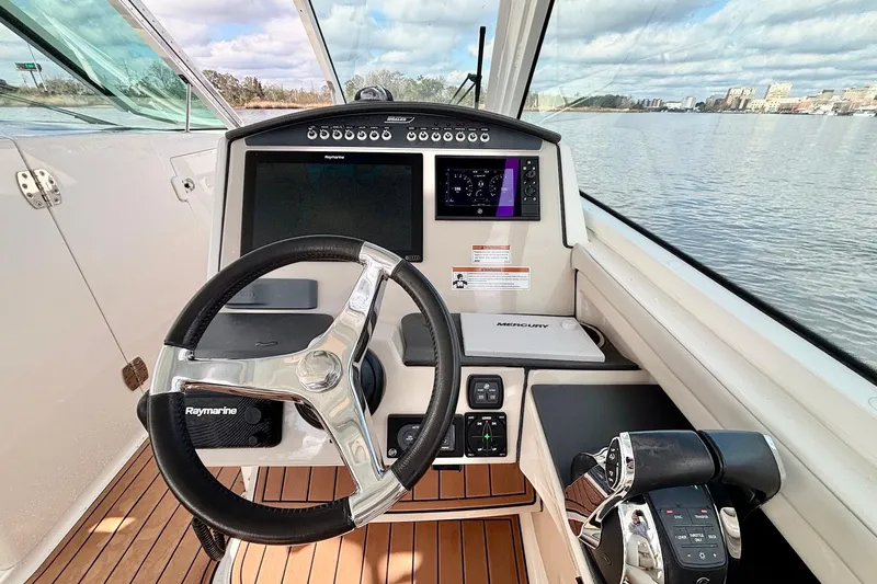 Slide: The Image of 2021 Boston Whaler 320 Vantage helm with Raymarine electronics and Mercury controls on water. - 12