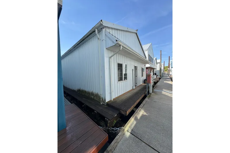 The Image of White Larson Boat House, 60', 2005 model, dockside view with blue sky background. - 1