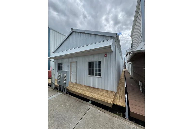 Slide: The Image of Floating boathouse with metal siding, Larson Boat House 60', 2005 model, under cloudy sky. - 5
