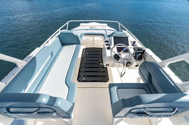 Slide: The Image of 2023 Scout 530 LXF boat interior with helm and seating, on calm water. - 31