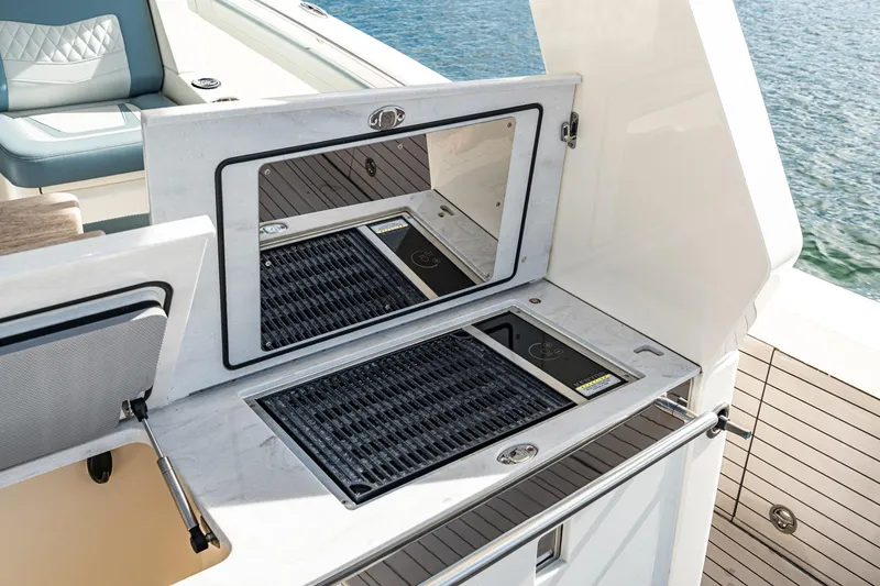 Slide: The Image of 2023 Scout 530 LXF boat grill station with sleek design and water backdrop. - 49