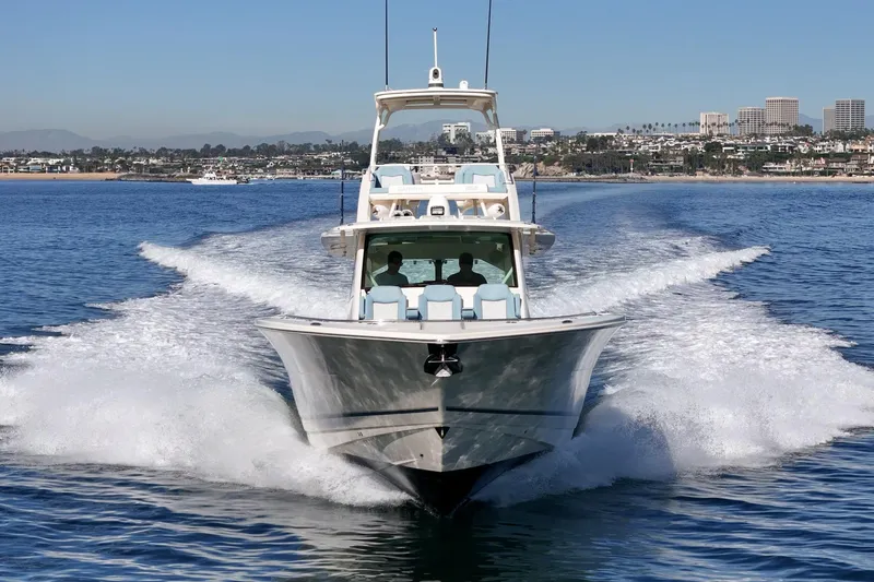 Slide: The Image of 2023 Scout 530 LXF cruising on open water with city skyline in background. - 7