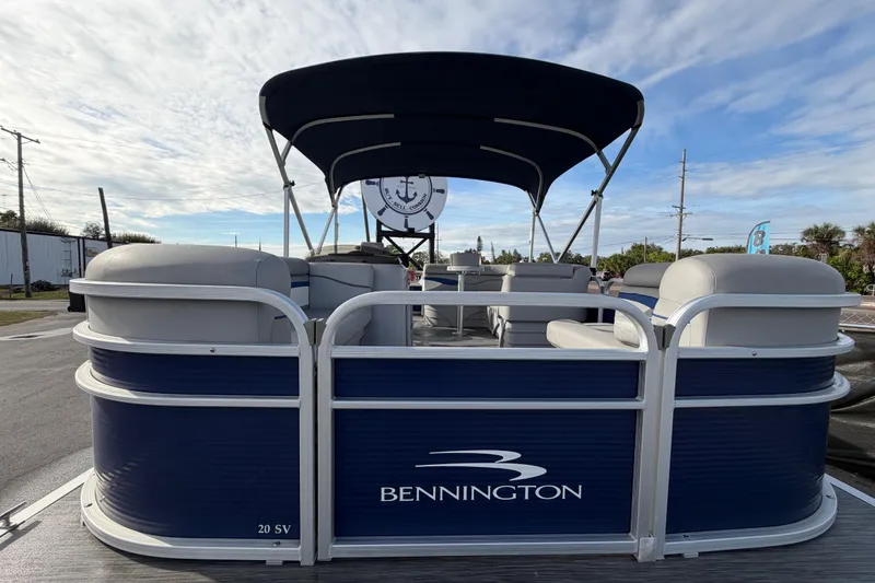 Slide: The Image of 2021 Bennington 20 SV pontoon boat with canopy, parked outdoors under a cloudy sky. - 12