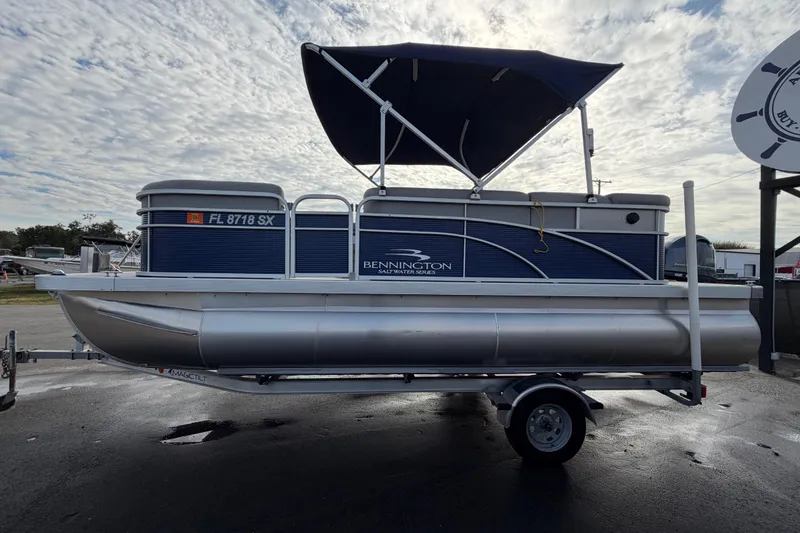 Slide: The Image of 2021 Bennington 20 SV pontoon boat with canopy on trailer, under cloudy sky. - 8