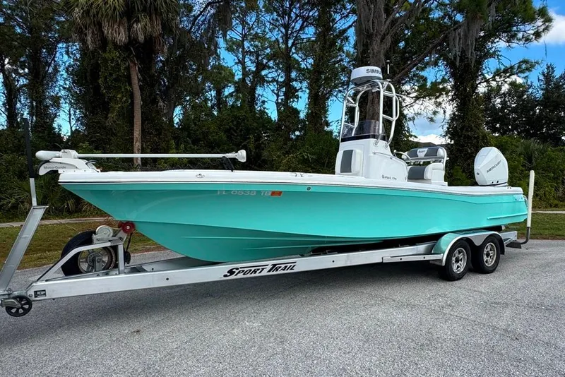 Slide: The Image of 2021 BlackJack 256 Coastal boat on trailer, parked outdoors with trees in background. - 1
