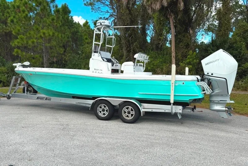 Slide: The Image of 2021 BlackJack 256 Coastal boat on trailer, turquoise hull, Mercury outboard engine. - 2