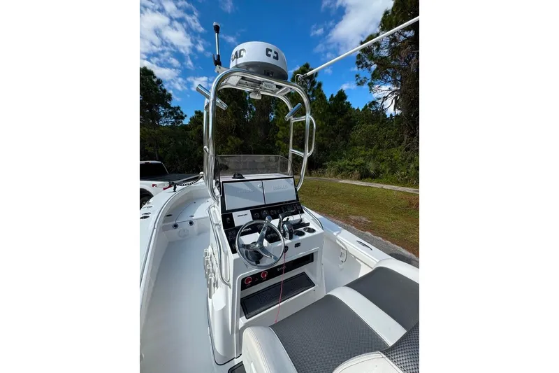 Slide: The Image of 2021 BlackJack 256 Coastal boat interior with steering console and seating, under a clear blue sky. - 26