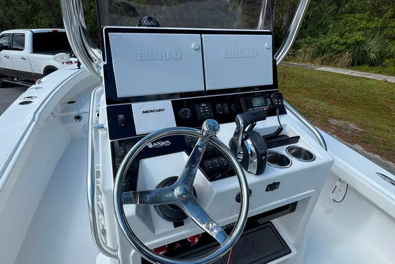 Slide: The Image of 2021 BlackJack 256 Coastal boat dashboard with steering wheel and navigation controls. - 27