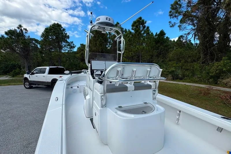 Slide: The Image of 2021 BlackJack 256 Coastal boat with center console, parked near a white truck, surrounded by trees. - 35