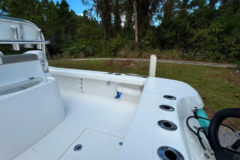Slide: The Image of 2021 BlackJack 256 Coastal boat interior with rod holders and storage, surrounded by greenery. - 36
