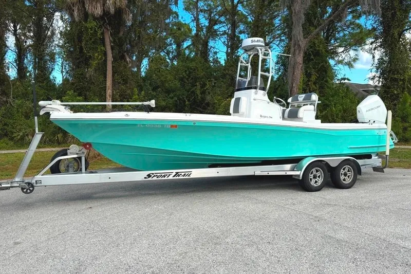 Slide: The Image of 2021 BlackJack 256 Coastal boat on trailer, vibrant turquoise hull, parked outdoors. - 40