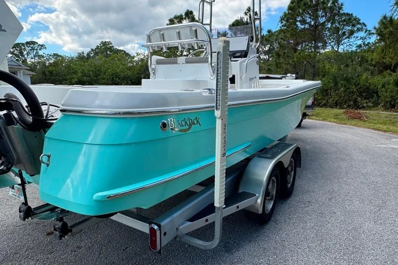 Slide: The Image of 2021 BlackJack 256 Coastal boat on trailer, turquoise hull, parked outdoors. - 7