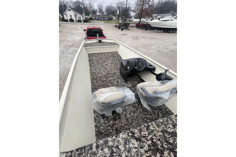 Slide: The Image of 2001 SeaArk 2272 MV boat interior with steering console and two seats, parked outdoors. - 5