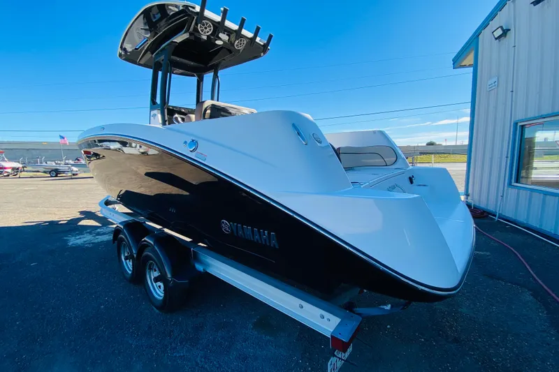 Slide: The Image of 2023 Yamaha Boats 255 FSH Sport E on trailer, sleek design, outdoor display. - 2