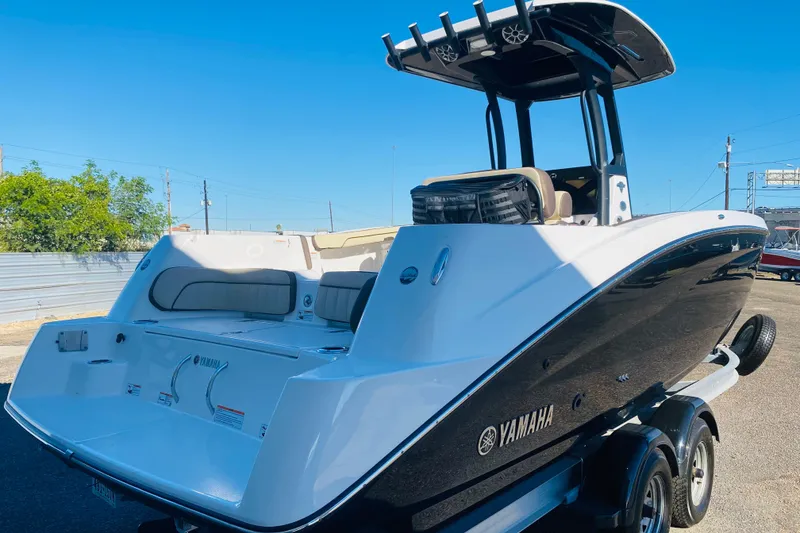 Slide: The Image of 2023 Yamaha Boats 255 FSH Sport E, sleek design, parked on trailer, sunny day. - 3
