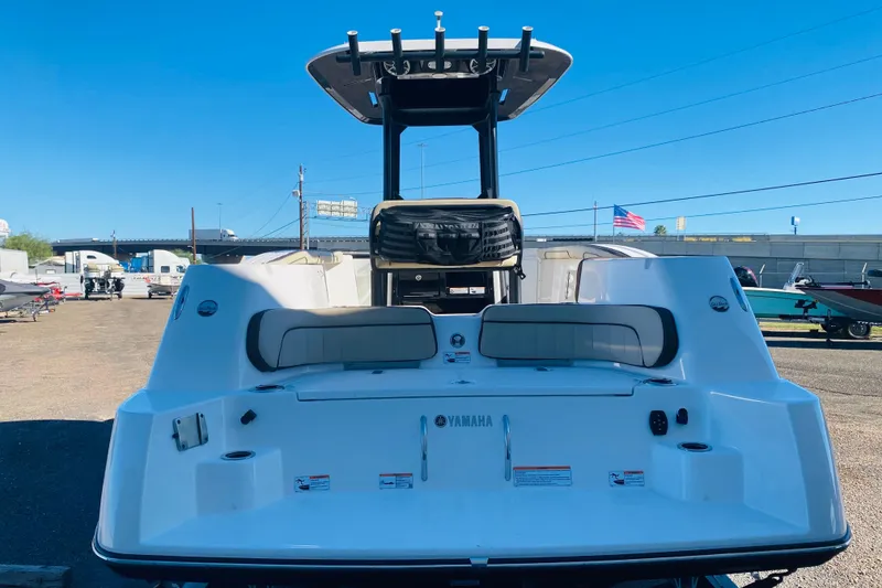 Slide: The Image of 2023 Yamaha Boats 255 FSH Sport E, rear view, in a boatyard under clear blue sky. - 4