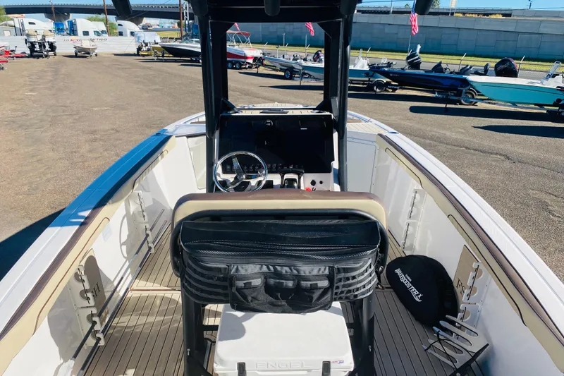 Slide: The Image of 2023 Yamaha Boats 255 FSH Sport E interior with steering wheel and seating, docked outdoors. - 5