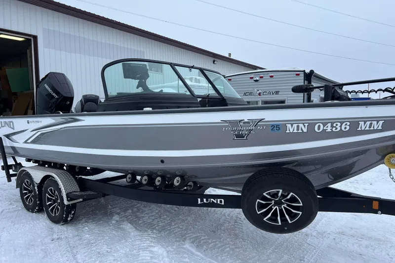 Slide: The Image of 2023 Lund 2175 Pro-V boat on trailer by the water, showcasing sleek design. - 2