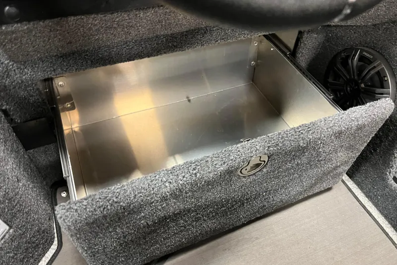 Slide: The Image of Storage compartment in 2023 Lund 2175 Pro-V boat, featuring carpeted interior and metal lining. - 36